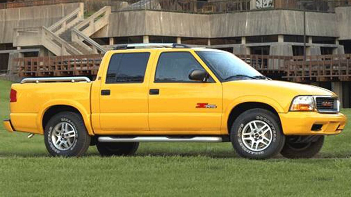 2003 GMC Sonoma in yellow parked on grass.