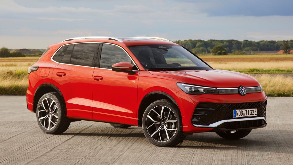 2025 Volkswagen Tiguan in red with a grassy field in the background.