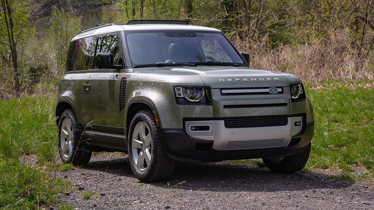 2024 Land Rover Defender on the road by trees.
